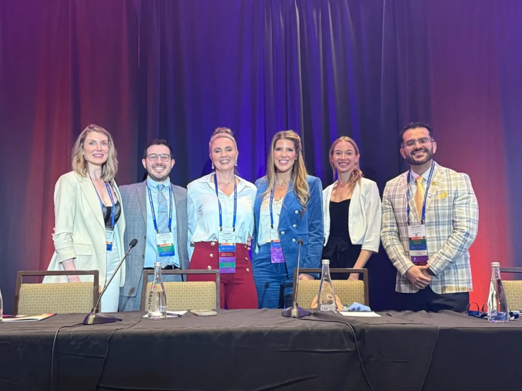 Multiple Allied Health Members standing in a row behind a table at the AACS Annual Scientific Meeting